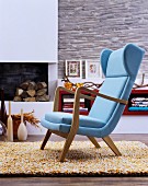 Pale blue easy chair on woollen rug in front of fireplace in living room