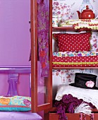 Brightly coloured, vintage accessories and clothing in open wooden cupboard with glass doors
