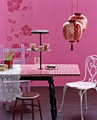 Stilmix in Pink: Esstisch mit Etagere, verschiedenen Stühlen und asiatischen Papierlampen