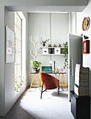 Designer Schalenstuhl vor Schreibtisch mit Böcken in kleinem Zimmer mit raumhohem Sprossenfenster