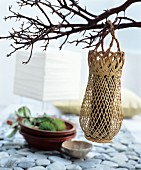 Dekoideen im fernöstlichen Stil: Geflochtene Vase aufgehängt an Zweigen
