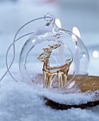 Festive bauble with glass reindeer inside amongst artificial snow
