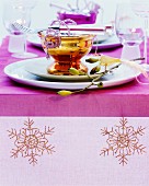 Table festively set with embroidered runner and silvered glass dishes in bright colours