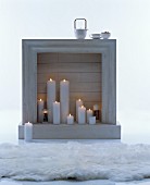 White fake fireplace festively decorated with lit white pillar candles