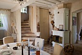 Dining area in front of winding staircase and fireplace in open-plan interior of country house