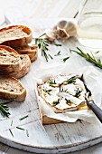 Baked cheese with rosemary and garlic served with baguette