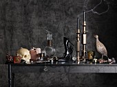 Verschiedene Accessoires und Dekoobjekte im antrazithfarbenen Gothic-Ambiente (Kerze als Totenschädel, Pumps, Vogelfigur, etc.)