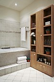 Potted plants on shelves in wooden cabinet in tiled bathroom