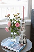 Vases of roses, book about Capri and candlestick on side table