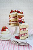 An Eton Mess layer cake with strawberries, raspberries and blueberries, sliced, with a slice on a plate