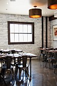 An industrial style Italian restaurant with wooden tables and metal chairs