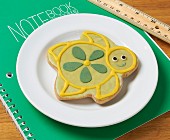 A turtle shaped biscuit decorated with icing on a notebook
