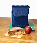 A peanut butter sandwich and an apple as a snack with a lunch bag