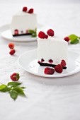 Two slices of coconut cheesecake with fresh raspberries