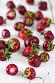 Fresh strawberries scattered on white wooden surface