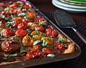 A puff pastry tart with red and yellow cherry tomatoes and basil
