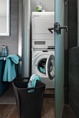 Offene satinierte Glastür und Blick in minimalen Stauraum mit Trockner und Waschmaschine in zeitgenössischem Bad