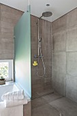 A shower cabin with a rain shower head and grey wall tiles in a designer bathroom