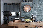 Wooden dining table, candle sconce on stone wall and kitchen integrated into niche
