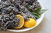 Elderberries with lemons in a white bowl on a marble surface