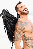 A topless man wearing black angel's wings