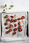 Oven-roasted zebra tomatoes on a baking tray lined with baking paper (seen from above)