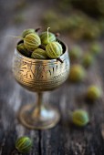 Green gooseberries in an antique silver goblet