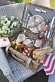 An open picnic basket with crockery, wine, bread and tomatoes