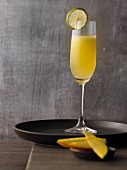 A champagne cocktail with mango and limes