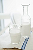 Almond milk in a glass and a bottle on a wooden table