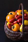 Various different coloured tomatoes in a basket