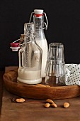 Homemade almond milk in flip-top bottles on a wooden tray