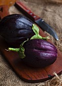 Two fresh aubergines on a wooden board