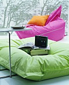 Enormous, brightly coloured beanbags in front of wall hanging with forest motif