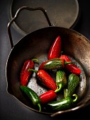 Red and green chilli peppers in an iron pot