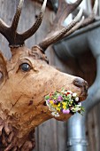 Carved wooden stag's head decorated with wild flowers on wooden wall