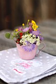 Tasse mit Wiesenblumen auf ländlicher Serviette
