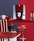 Bright red, glossy bar stool at red kitchen counter with espresso machine and white cups