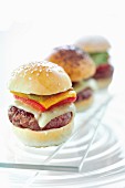 Three mini hamburgers in a row on a glass platter