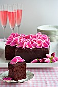Chocolate cake decorated with pink rose petals and served with champagne cocktails