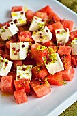 Feta and watermelon salad garnished with lime zest and pink peppercorns