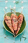 Grilled chicken skewers on a leaf-shaped plate