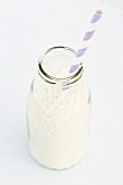 Coconut flakes in a milk bottle with a straw