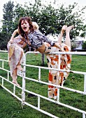Two woman climbing a fence
