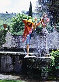 Junge Frau in transparentem Shirt und Jeans an Brunnen