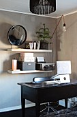 Notebook on stand on dark wooden desk in front of office utensils on white shelves mounted on pale brown wall