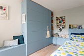 Fitted cabinets with integrated storage bench, fitted cupboards and bed headboard painted blue