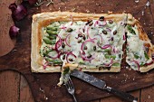 Puff pastry tart topped with goats cheese, asparagus and red onions