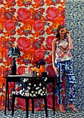 Young woman in room with different patterns on wallpaper, carpet, armchair and clothes