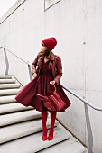Frau mit Kleidung in verschiedenen Rottönen steht auf Treppe